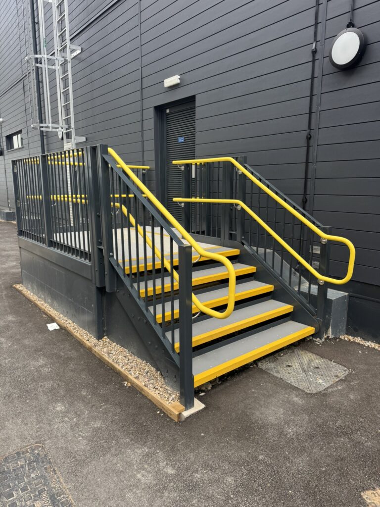 External steel access stairs with yellow handrails and balustrades